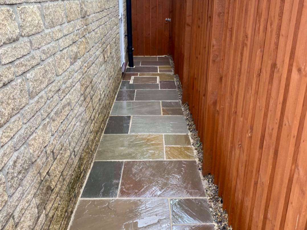 Narrow alleyway showing freshly cleaned patio paving slabs.