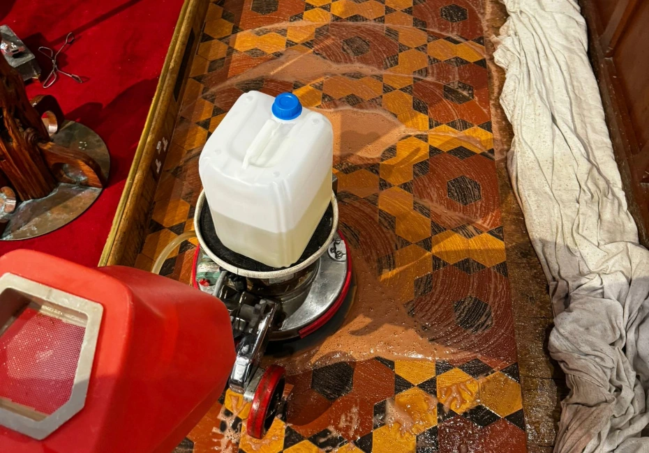 Colourful church floor tiles are cleaned while pews are protected with cloth.