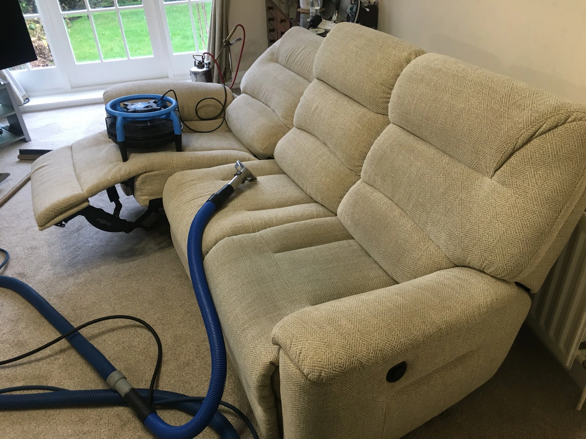 cream sofa with blue coloured cleaning equipment sat on top