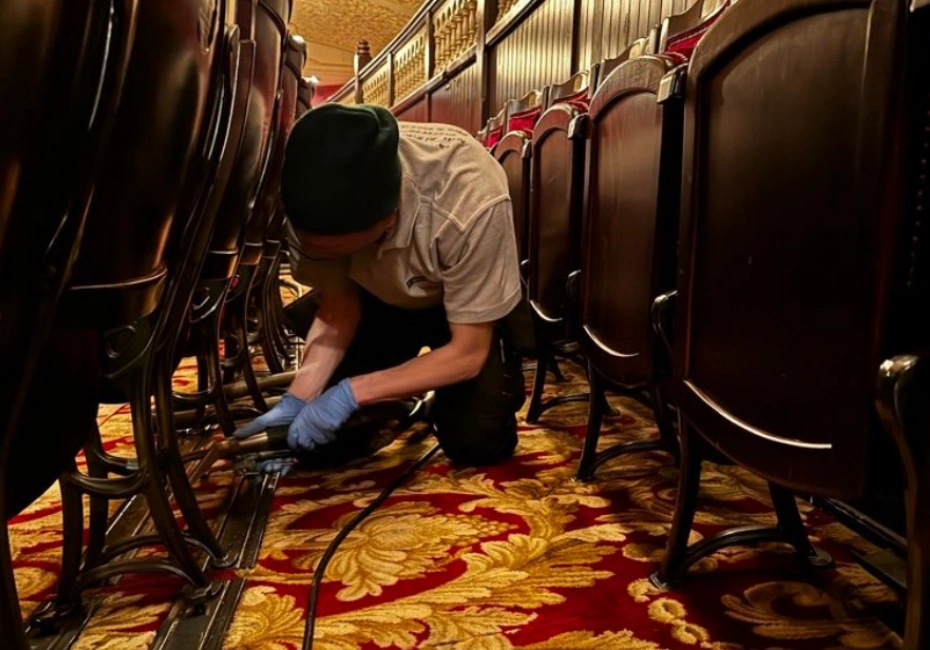 A Paul Dyson employee cleaning the carpets underneath a row of seats at the Theatre Royal.