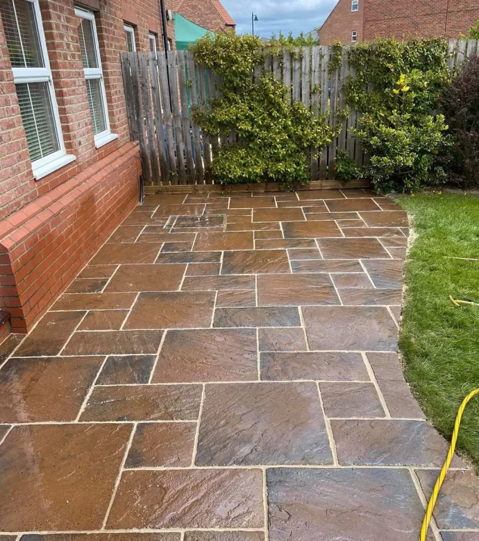Newly cleaned flagstone patio next to a house and lawn.