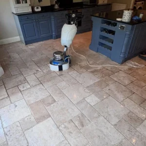 Natural stone flooring being professionally restored in kitchen with blue cabinetry.