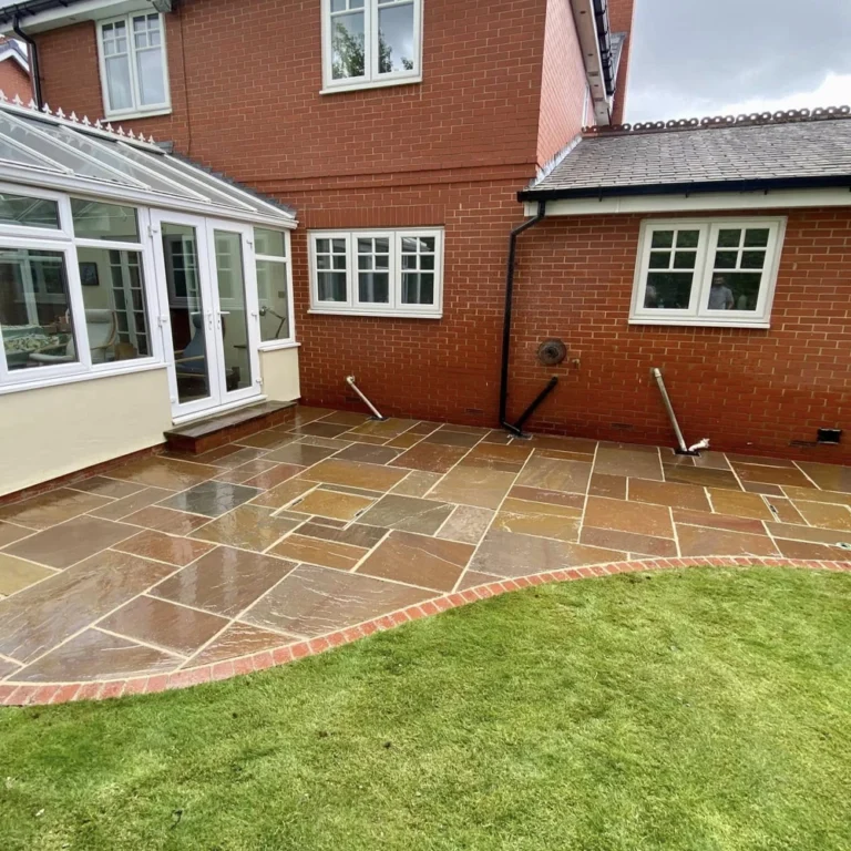 A high-angle view of a freshly sealed Indian Sandstone patio, highlighting the wet look finish that deepens the natural earthy tones of the stone.