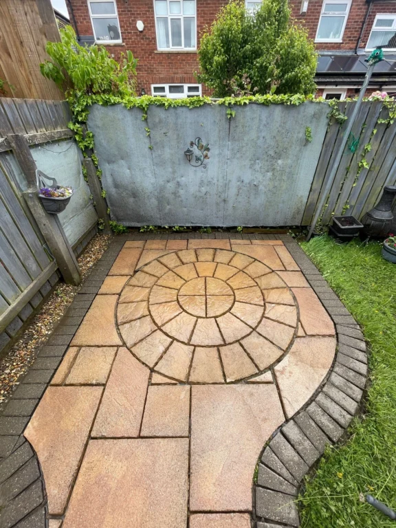 A decorative sandstone patio that has been washed and repointed with the weeds removed from between the paving slabs.