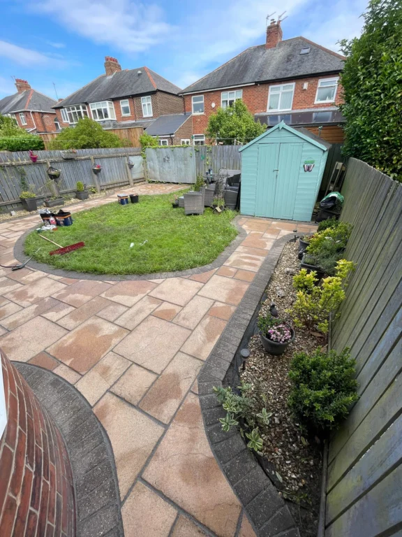 A bright, clean garden with freshly cleaned and repointed paving slabs encircling a small circle of grass.